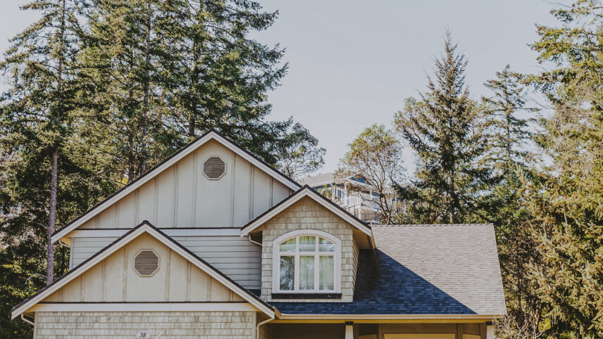 Charming house in View Royal, near Victoria, BC, featuring a gabled roof, light-colored siding, and surrounded by tall trees and a peaceful wooded setting