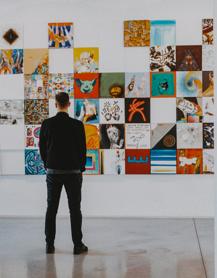 Visitor observing a vibrant art gallery wall in Rockland at 321 Art Street, a feature by Folio Group at Clover Residential in Victoria, BC