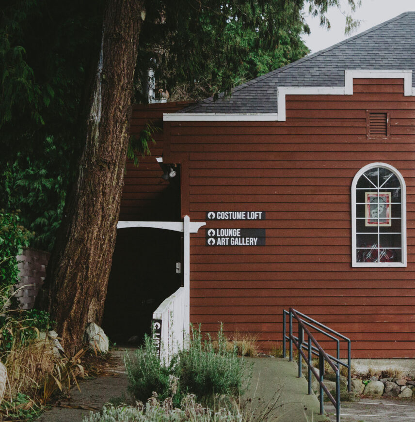 Exterior of a red wooden building with signage for