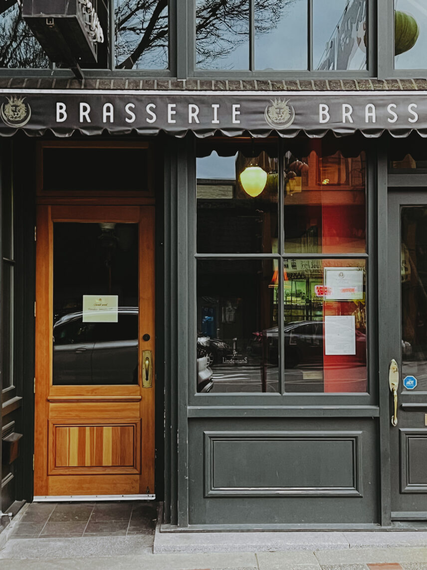 Exterior view of Brasserie storefront featuring wooden door and large glass windows