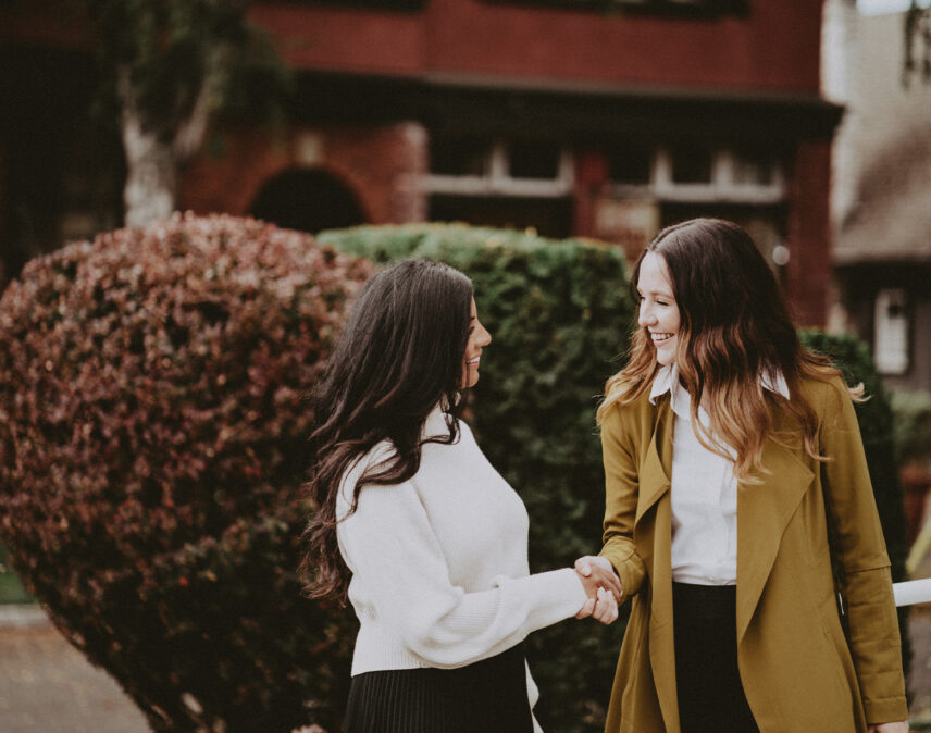 Hannah Hayworth and a colleague from Clover Residential sharing a handshake outside a charming Victorian-style building in Victoria, BC, symbolizing trust and partnership