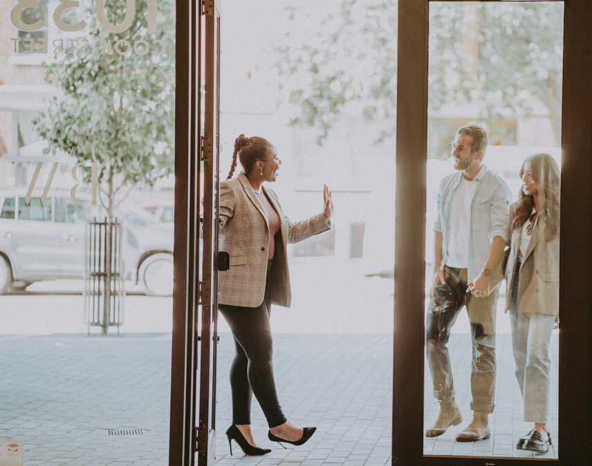 Professional real estate agent from Clover Residential warmly welcoming a couple into a property, emphasizing trust and hospitality in Victoria, BC
