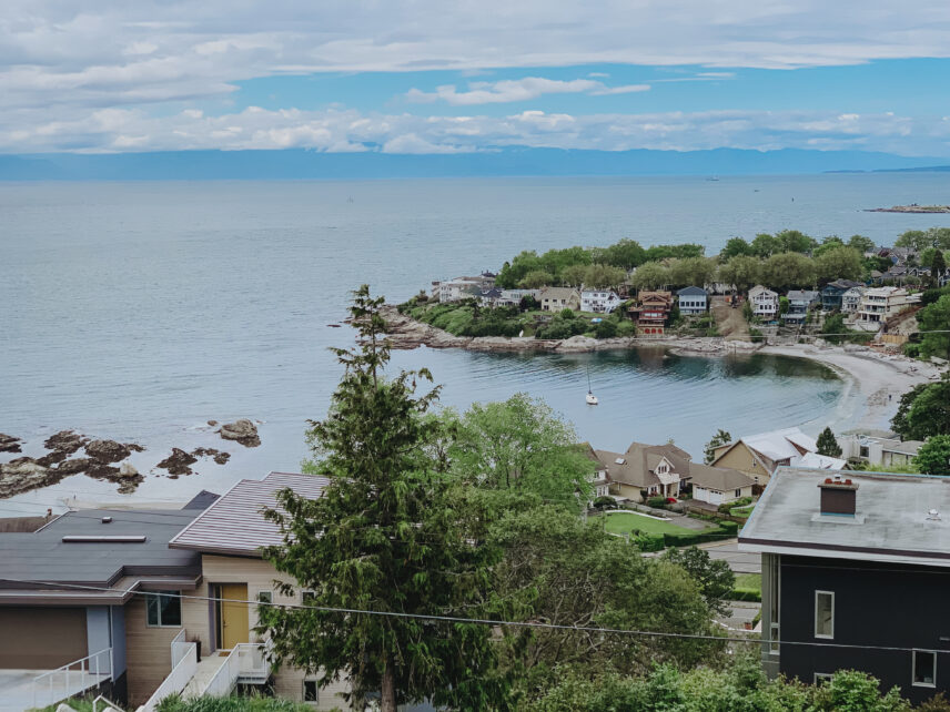A stunning aerial view of Fairfield, showcasing waterfront homes, lush greenery, and a serene beach, highlighting properties managed by Clover Residential in Victoria, BC
