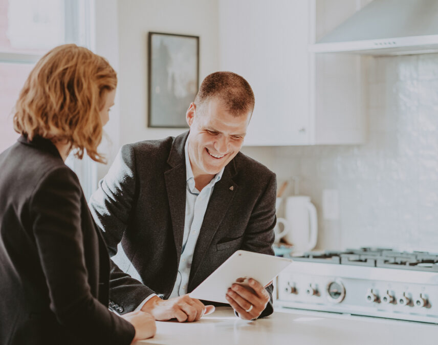 Ole Schmidt from Clover Residential smiling while reviewing property details with a client in a modern, sunlit kitchen, highlighting personalized real estate service in Victoria, BC