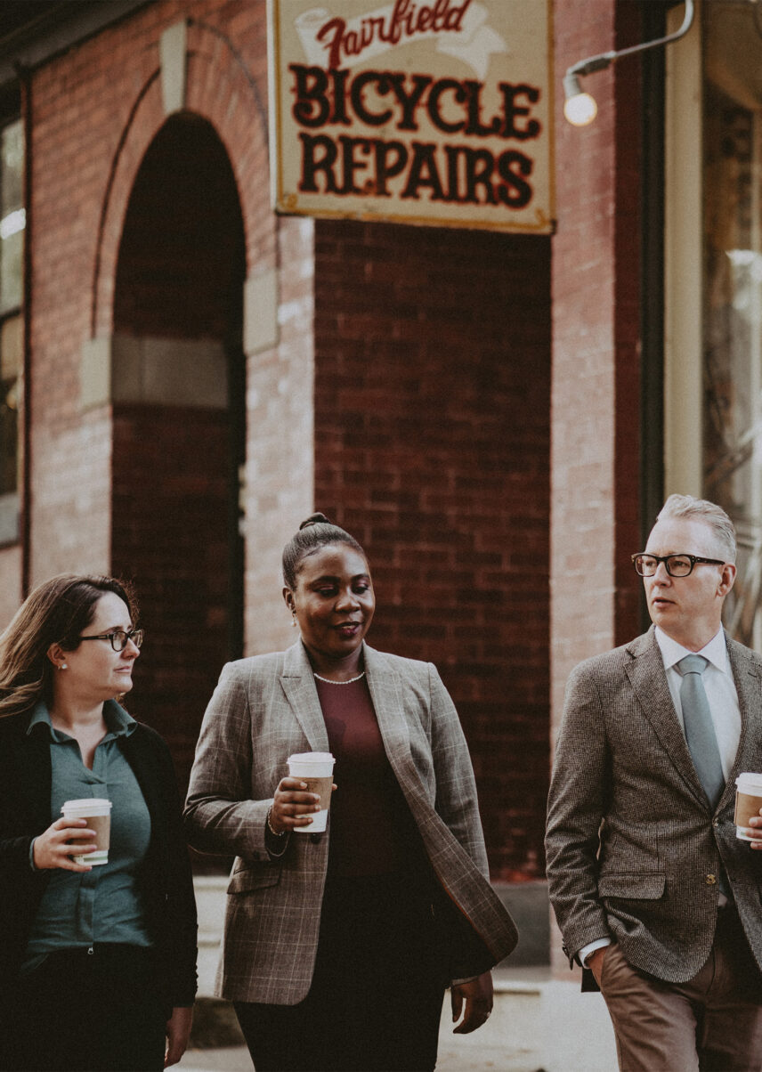 David Logan, accompanied by colleagues from Clover Residential, walking near Fairfield Bicycle Repairs in Victoria, BC, showcasing their community-focused approach to real estate services
