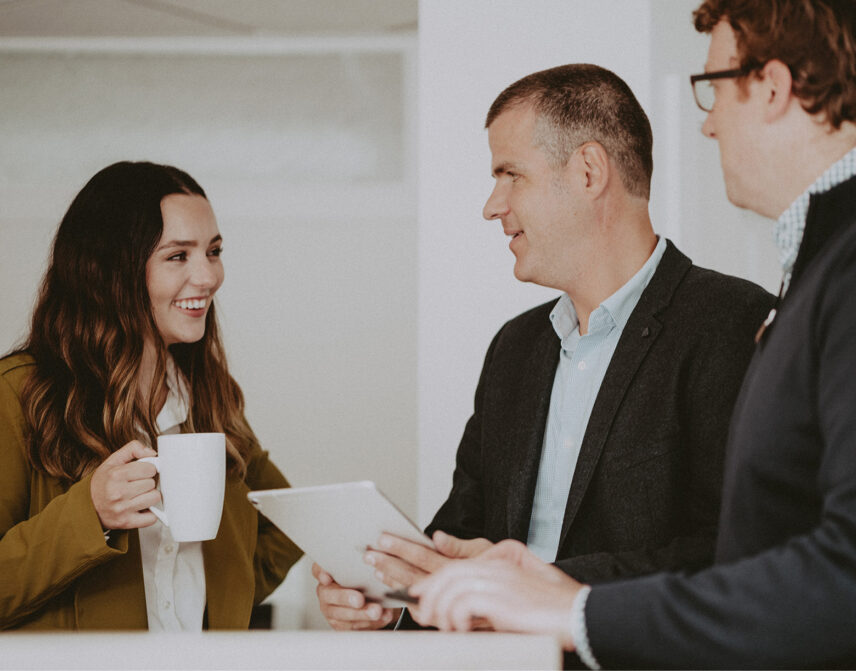 Ole Schmidt, Brian Ogilvie, and Hannah Hayworth from Clover Residential engaging in a collaborative discussion in a bright and inviting space, reflecting their teamwork and client-focused approach in Victoria, BC