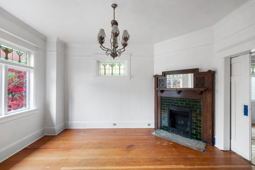 Elegant living room at 624 Cornwall Street Victoria BC listed by Folio Group at Clover Residential featuring stained glass windows a vintage fireplace with green tile and hardwood floors in the Fairfield neighborhood