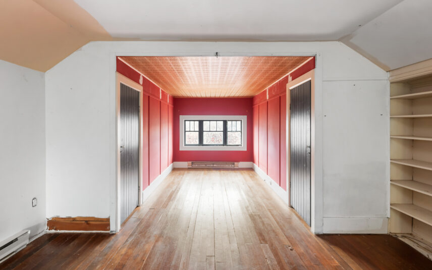 Interior view of 624 Cornwall Street Victoria BC listed by Folio Group at Clover Residential featuring a bright room with red accent walls natural light hardwood flooring and built-in shelving in the Fairfield neighborhood