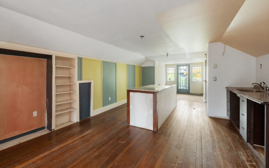 Open-concept kitchen and living area at 624 Cornwall Street Victoria BC listed by Folio Group at Clover Residential featuring hardwood floors built-in shelving and French doors leading to a balcony in the Fairfield neighborhood