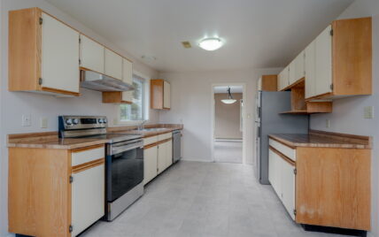 Bright kitchen featuring wood cabinetry, updated stainless steel appliances, and ample counter space at 1293 Layritz Place, managed by Clover Residential in Victoria, BC