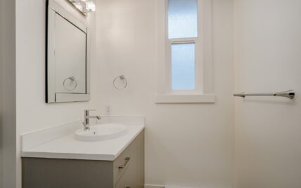 Modern bathroom with a quartz countertop vanity, vessel sink, framed mirror, and frosted window at 337 Robertson Street, managed by Clover Residential in Victoria, BC