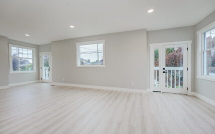 Spacious living room with bright windows, French doors leading to a private patio, and light wood laminate flooring at 337 Robertson Street, managed by Clover Residential in Victoria, BC