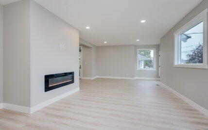 Open concept living room with a modern electric fireplace, light wood laminate flooring, and large windows at 337 Robertson Street, managed by Clover Residential in Victoria, BC