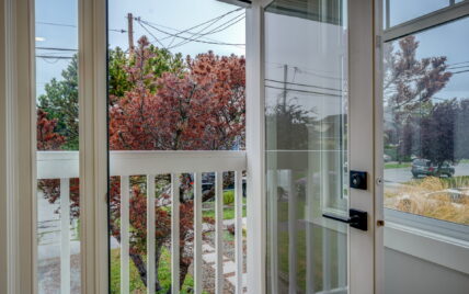 View from French doors leading to a small private patio with railings overlooking a quiet street and greenery at 337 Robertson Street, managed by Clover Residential in Victoria, BC