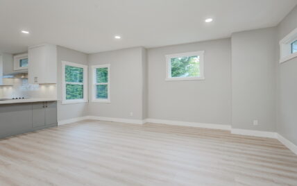 Bright dining area adjacent to the modern kitchen with large windows and light wood laminate flooring at 337 Robertson Street, managed by Clover Residential in Victoria, BC