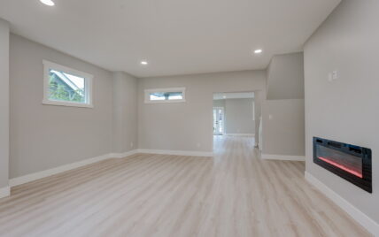 Spacious family room with a modern electric fireplace, light wood laminate flooring, and natural light from multiple windows at 337 Robertson Street, managed by Clover Residential in Victoria, BC