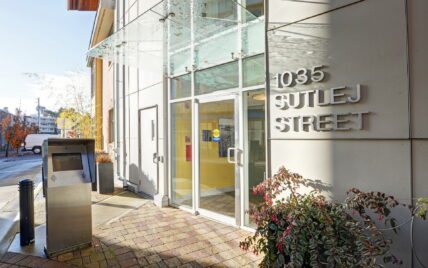 Front entrance of 1035 Sutlej Street, managed by Clover Residential in Victoria, BC, showcasing modern design with glass canopy and intercom system for rentals