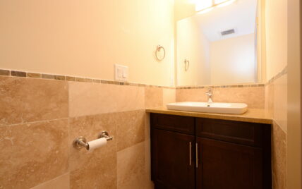 Powder room with tiled walls, modern vanity, and large mirror at 1035 Sutlej Street, Victoria, BC