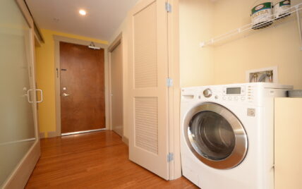 In-unit laundry with front-loading washer and storage shelf at 1035 Sutlej Street, Victoria, BC