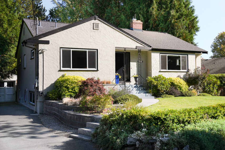 Front exterior of 711 Richmond Avenue, a home in Fairfield, Victoria BC, set back from the street with a landscaped front yard and mature trees.